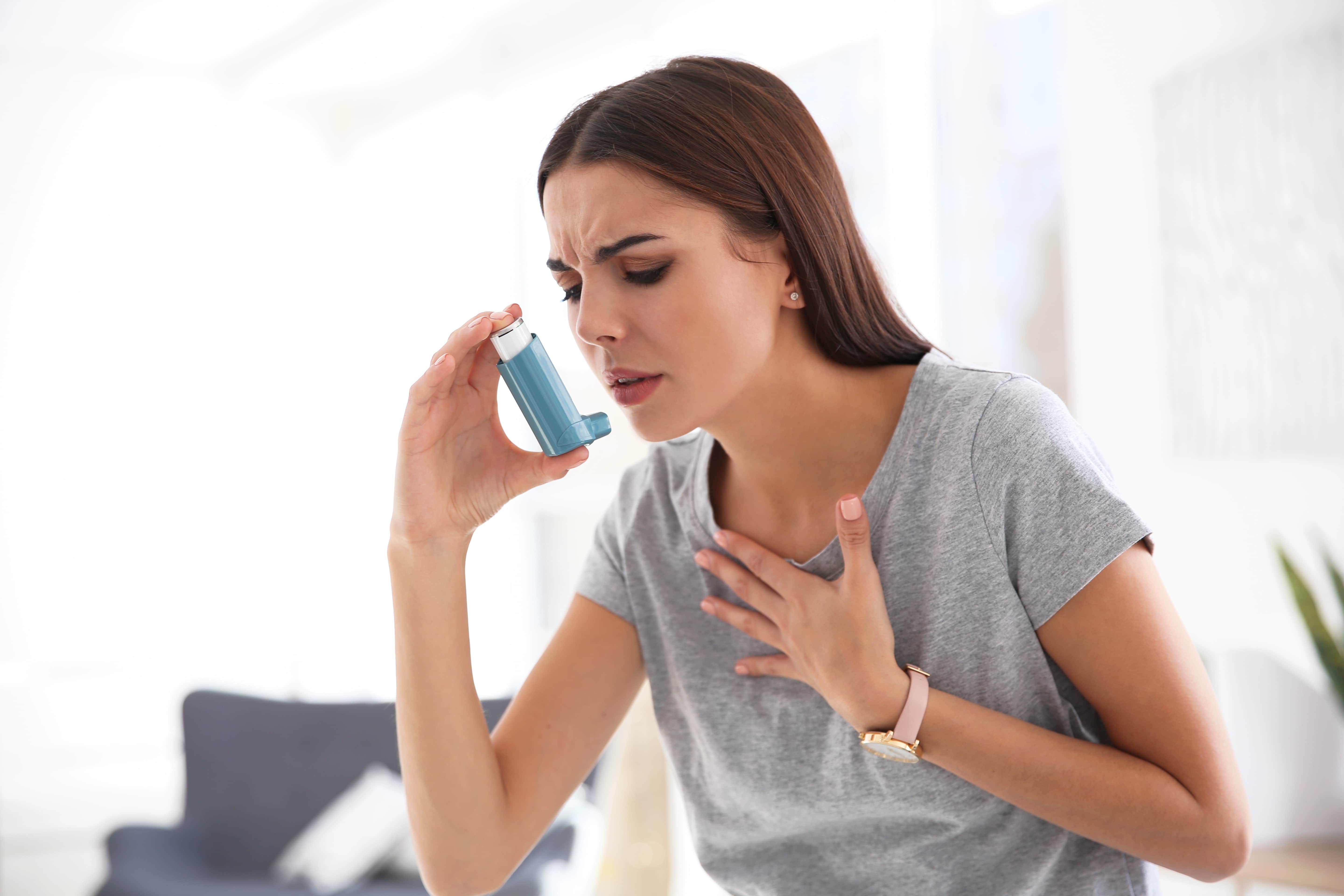Woman using a rescue inhaler to manage asthma attack symptoms