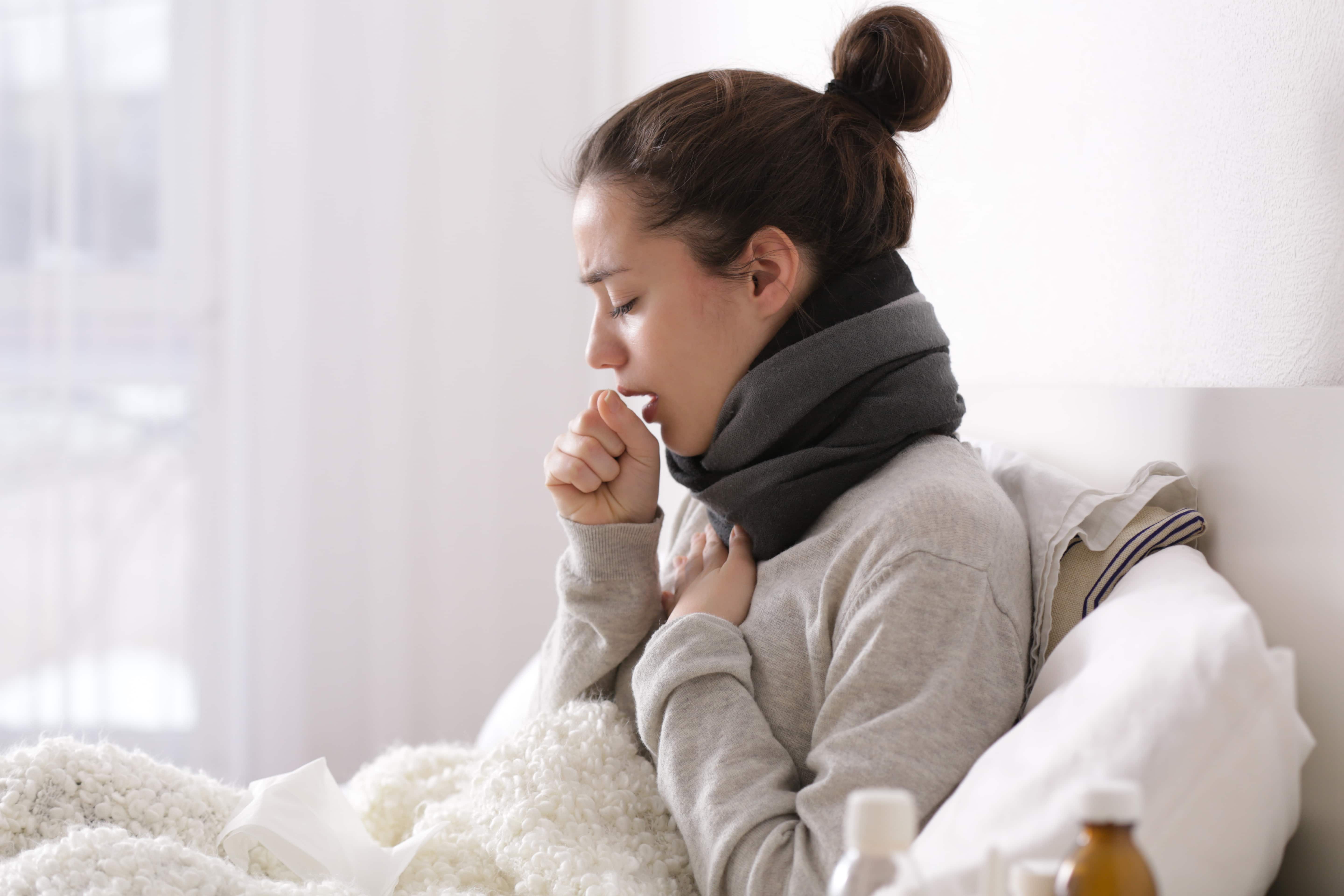 Woman coughing and holding her throat experiencing severe sore throat symptoms