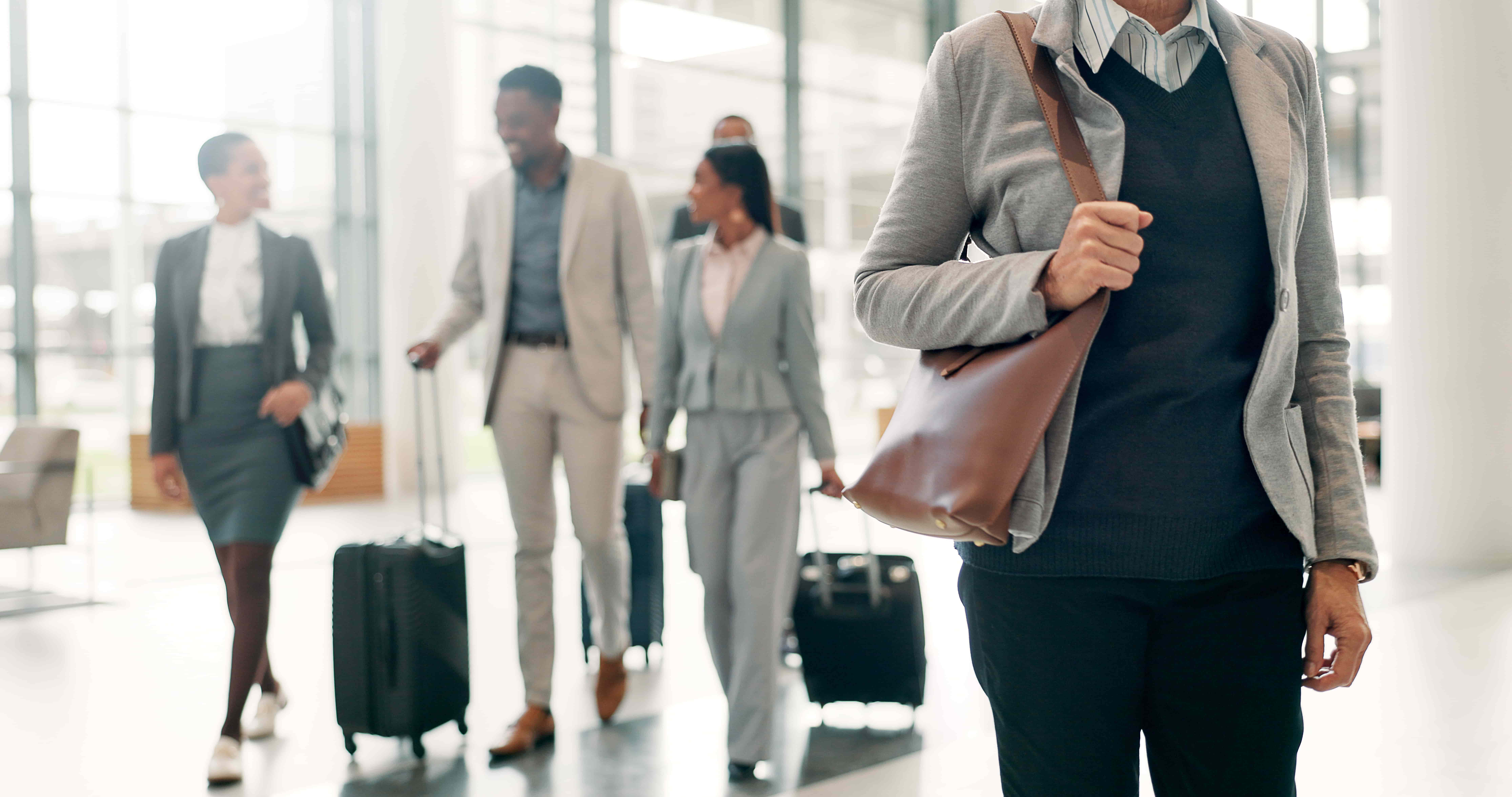 Business travelers walking through airport terminal with luggage representing flight changes and travel delays