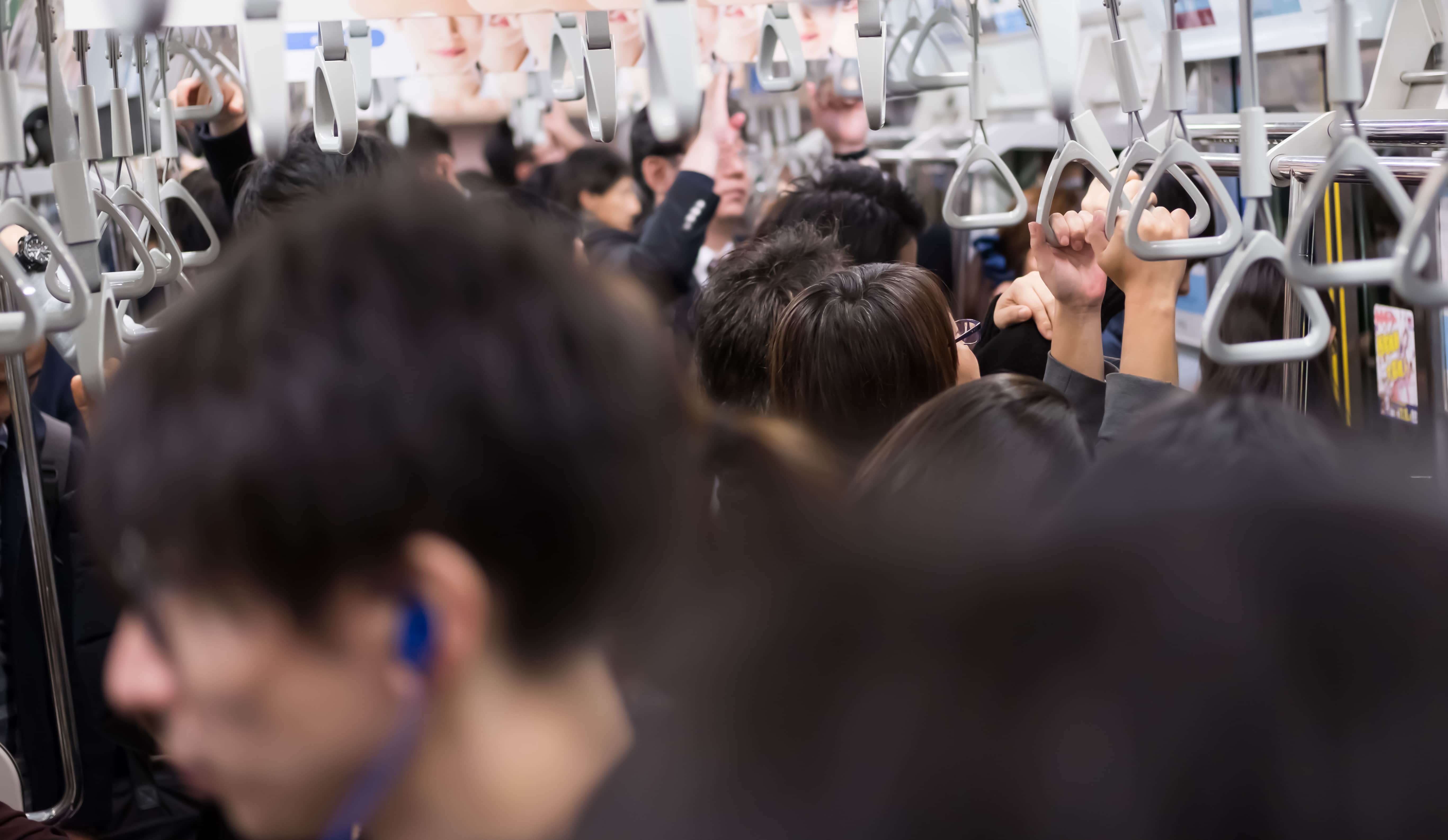 Crowded Japanese train during winter rush hour with passengers in heavy coats